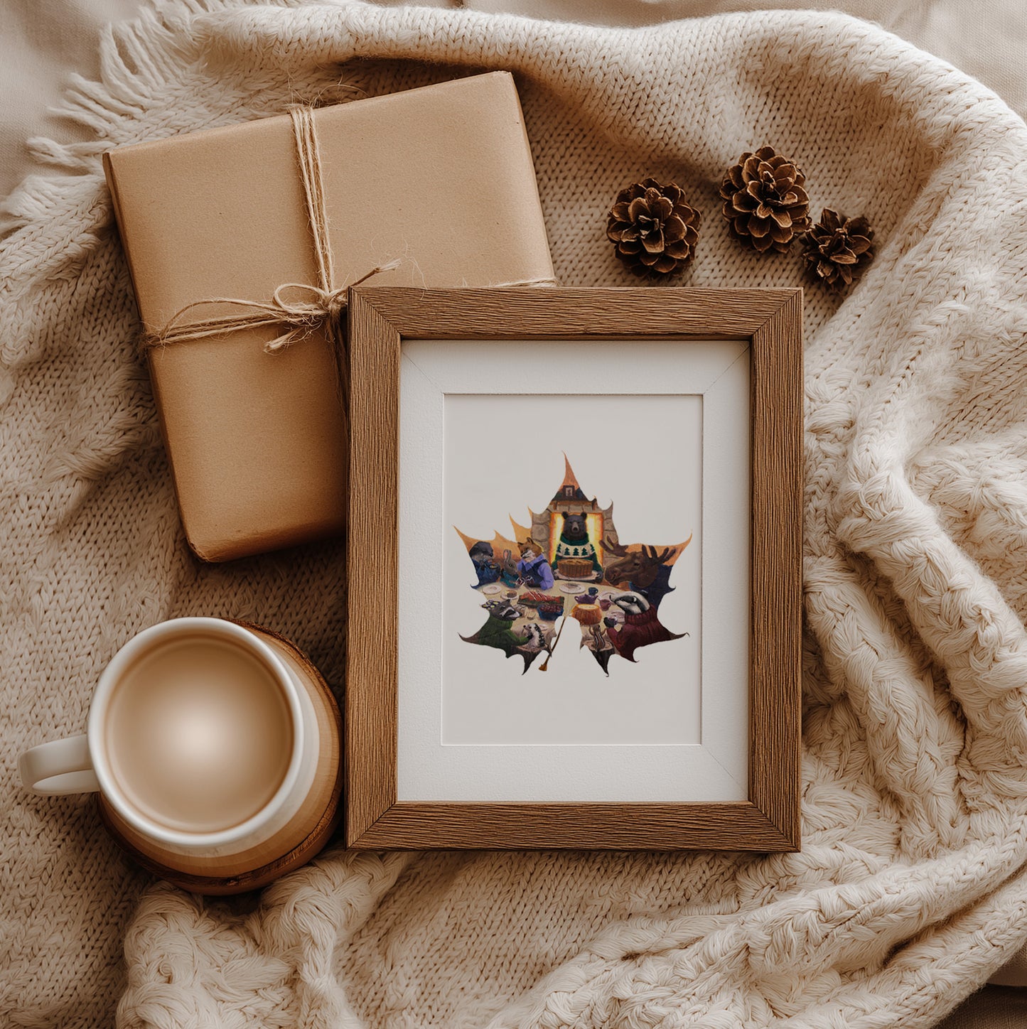 Framed artwork with a leaf design, wrapped gift, and mug on a textured surface