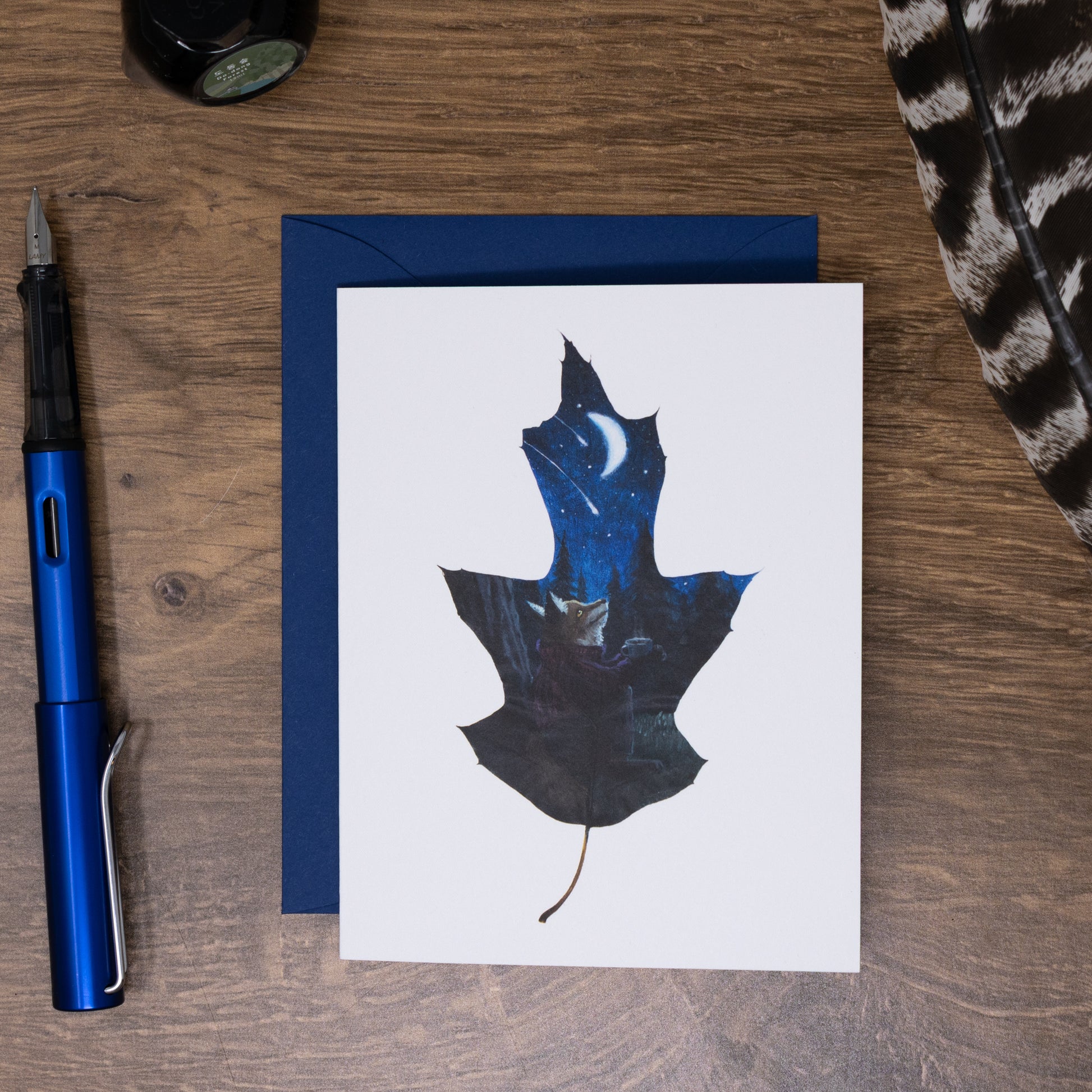 greeting card with a blue envelope on a desk with a fountain pen and ink