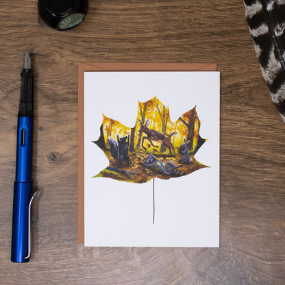 Greeting card with a leaf design on a wooden surface with a pen and other items.